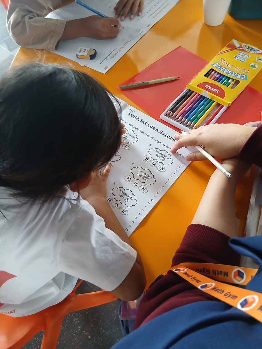 Math Coach mendampingi anak mengerjakan lembar kerja Lebih Satu dan Kurang Satu di The Arena Math Gym