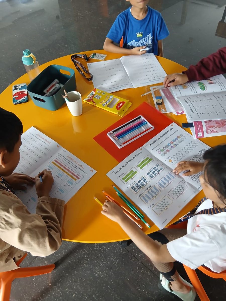 Empat anak mengerjakan worksheet di meja bundar oranye The Arena Math Gym